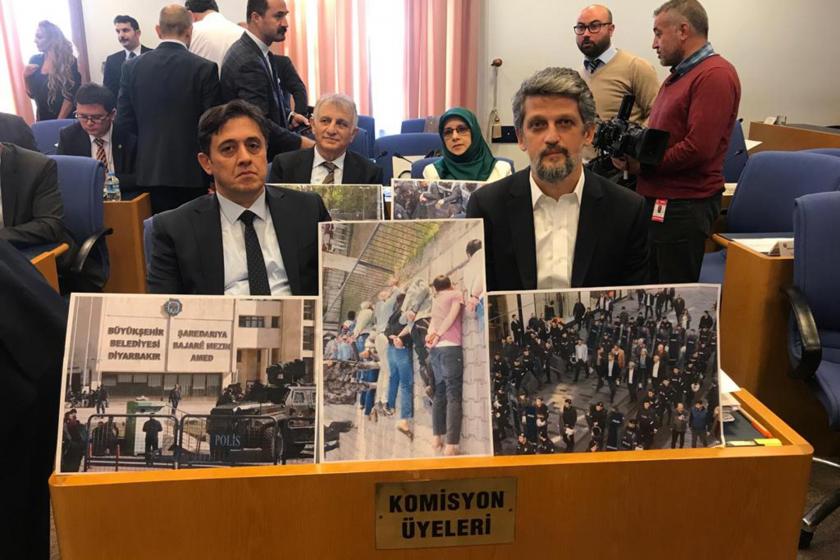 Komisyon üyeleri yazan sıralarda oturan HDP'li milletvekilleri ellerinde opeasyonlara dair büyük fotoğraflar tutuyor.