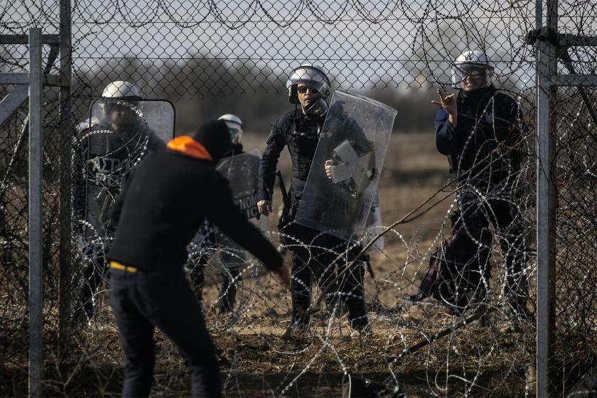 Dikenli tellerin ardında bekleyen Yunanistan polisi ve telleri geçmeye çalışan mülteci