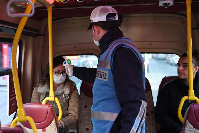 Zabıta dolmuşta bir yolcunun ateşini ölçüyor.