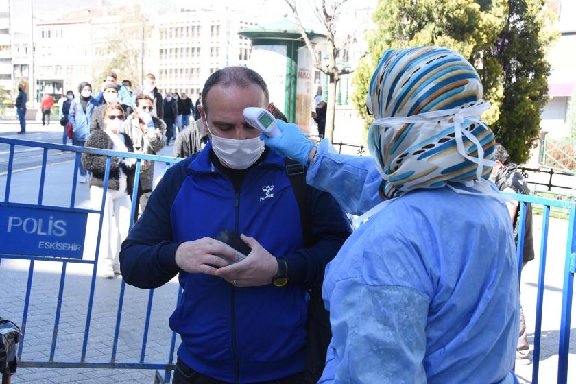 Ateş kontrolü yapan bir görevli ve maskeli bir erkek