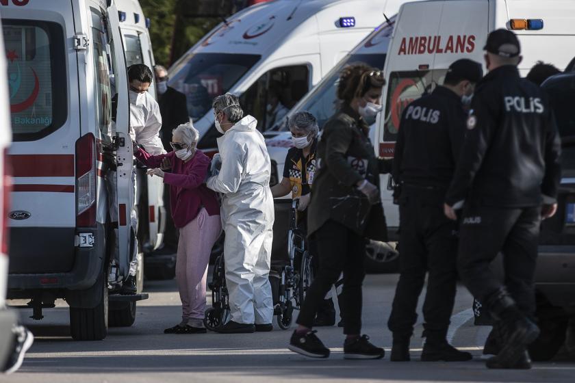 Yaşlı bir kadını ambulansa götüren görevliler.