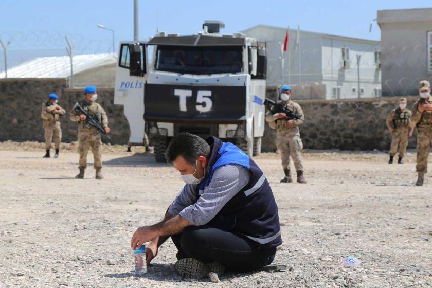 Mardin’in Mazıdağı ilçesinde Cengiz Holdinge ait işletmede, TOMA ve jandarmaların önünde yere oturmuş ve ağzı ile burnunu maske ile korumaya çalışan işçi. 