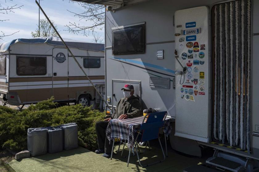 Karavan'ın önünde oturan maskeli bir erkek.