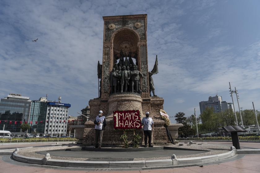 taksim anıtında hak-iş'in 1 mayıs çelengi ve başında duran iki kişi