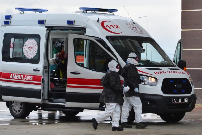 Koronavirüse karşı önlem olarak koruyucu ekipman giyen sağlık emekçileri ambulanstan inerken