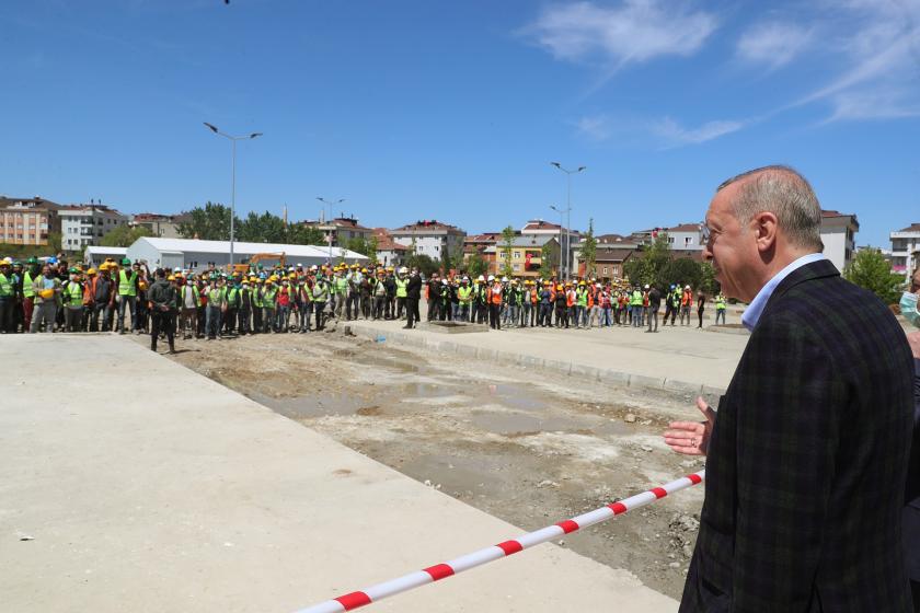 Cumhurbaşkanı Erdoğan'ın Sancaktepe'deki hastane inşaatını gezdiği sırada, yüzlerinde maske olmayan ve yan yana duran işçileri, araya çekilmiş güvenlik şeridinin arkasından selamladığı an.