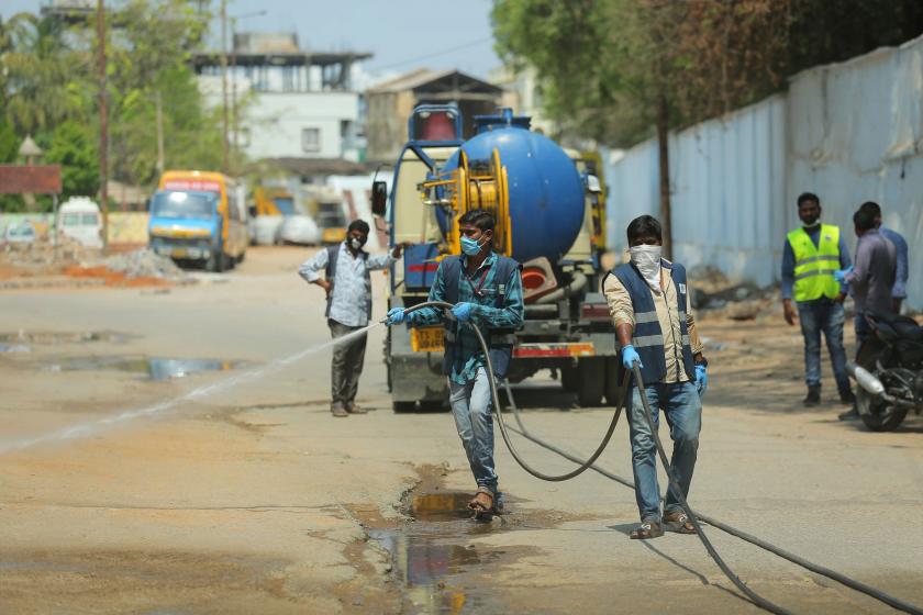 Hindistan'da sokağı dezenfekte eden görevliler