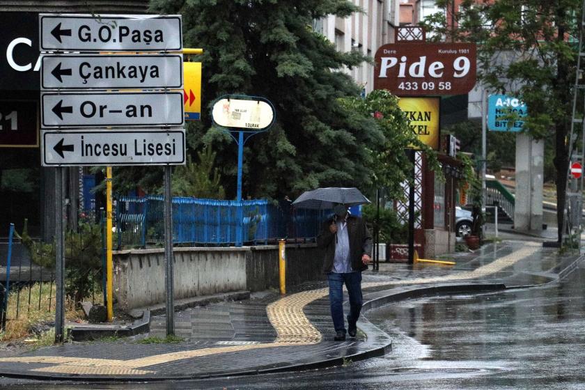 Tabelalar ve şemsiye ile yürüyen bir erkek (sağda)