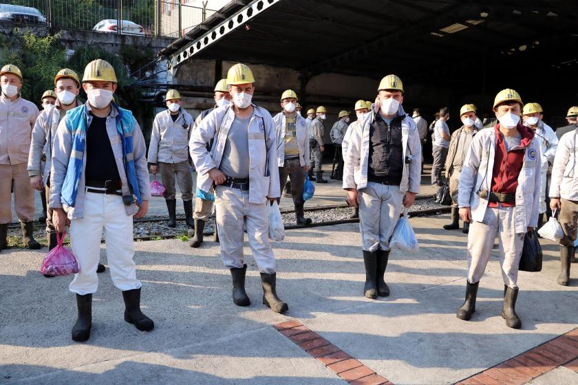 Ocak girişinde kısmen mesafe ile toplanmış maskeli madenciler.