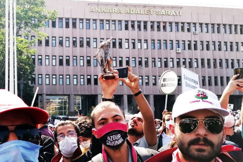 Polis saldırısına uğrayan avukatlardan biri, kafası ve terazisi koparılmış Themis heykelini gösteriyor.