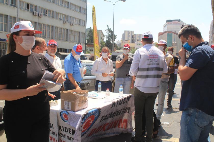 Kıdem Tazminatıma Dokunma yazılı masanın etrafında Türk-İş üyeleri