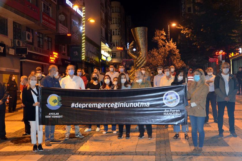 Deprem gerçeğini unutma pankartı ve arkasında anmaya katılanlar