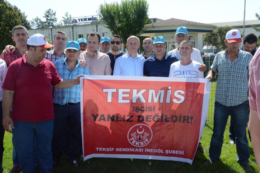 Tekmis işçisi yalnız değildir yazılı pankart arkasında işçiler 