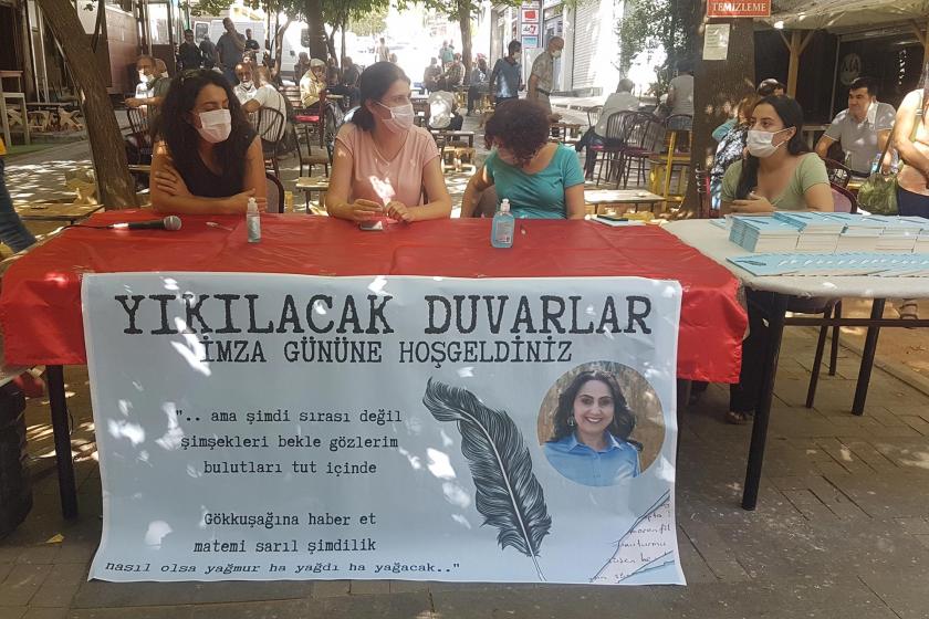 Yıkılacak Duvarlar imza gününe hoşgeldiniz pankartı ve masada duran 4 kadın 