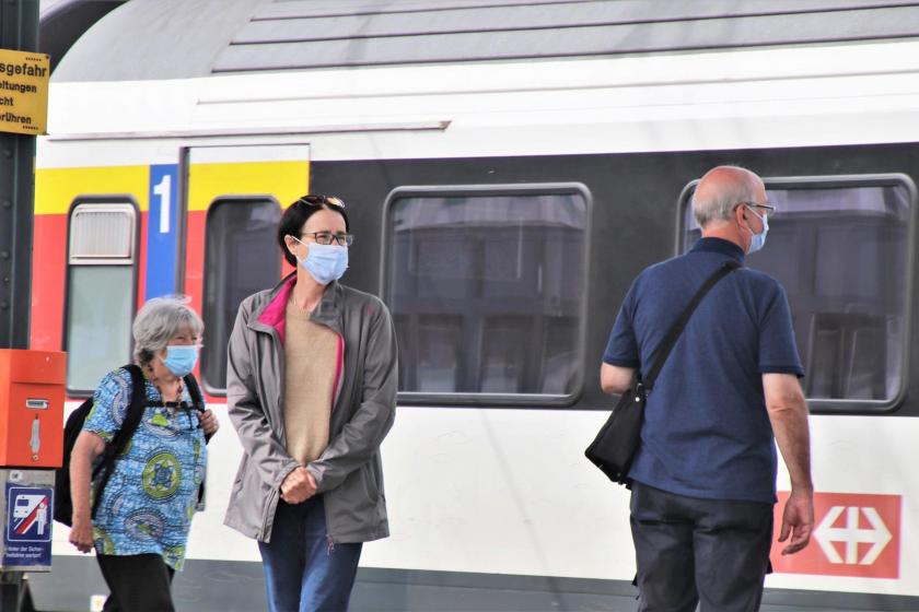 Tren istasyonunda bekleyen maskeli üç kişi