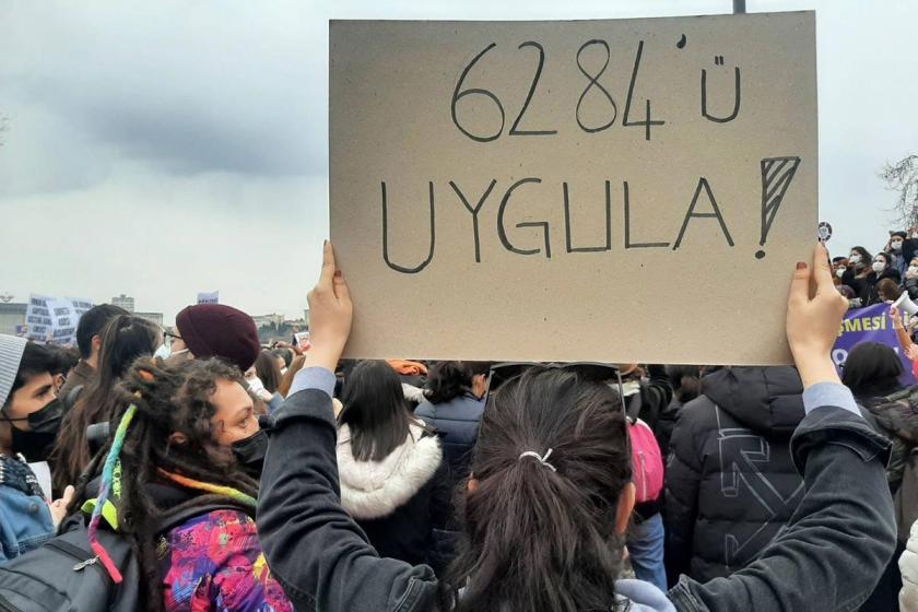 6284'ü uygula yazan pankart taşıyan bir kadın