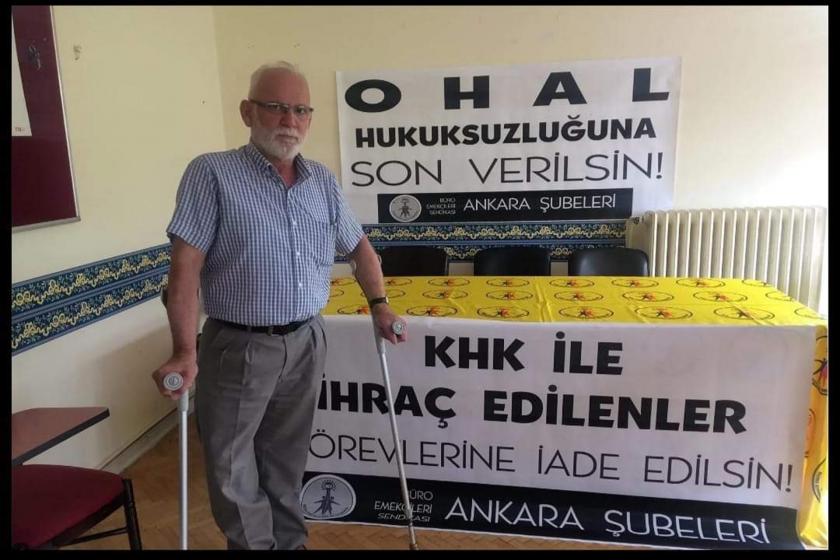 Mithat Tokur yürüteçleriyle KHK pankartının önünde ayakta duruyor