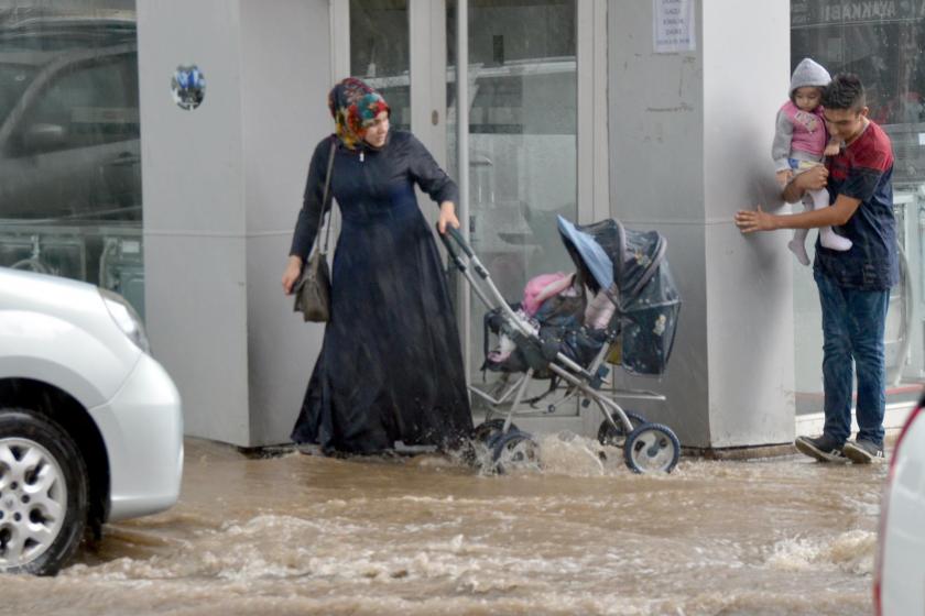 Su basan kaldırımlarda yürümeye çalışanlar