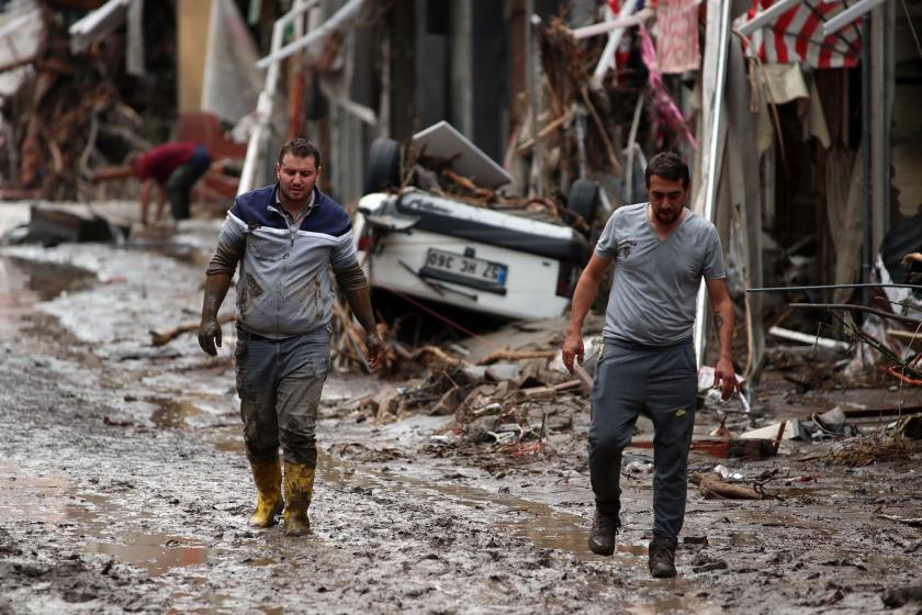 Kastamonu'da meydana gelen sel sonrası çamura bulanmış sokaklarda yürüyen iki kişi.