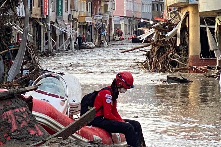 Sel bölgesinde bir botun üzerinde üzgün şekilde oturan kurtarma görevlisi