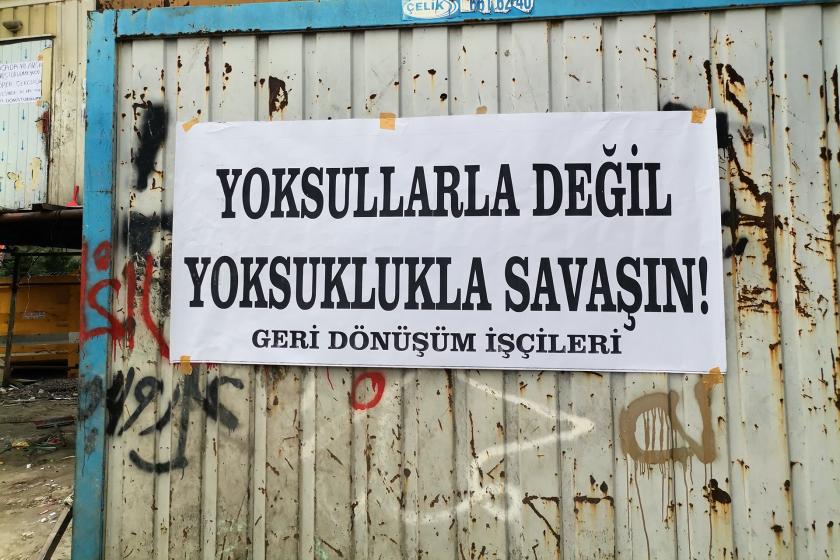 Geri dönüşüm işçilerinin basın açıklaması esnasında bir konteynere yapıştırılmış olan 'Yoksullarla değil yoksullukla savaşın' yazılı pankart.