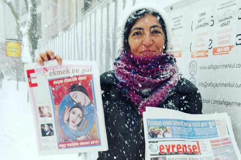 Elinde Ekmek ve Gül dergisi ve Evrensel gazetesini tutan, üzerine kar yağan bir kadın.