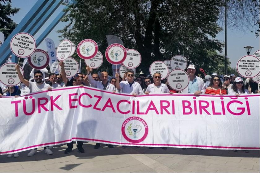 Türk Eczacıları Birliği pankartı. Pankartın arkasında eczacılar var, ellerinde döviz var.