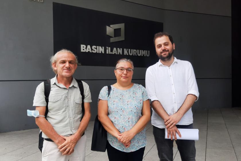 Basın İlan Kurumu tabelası önünde Rıza Doğan, Avukat Devrim Avcı ve Evrensel gazetesi yazı işleri müdürü Erdi Tütmez var.