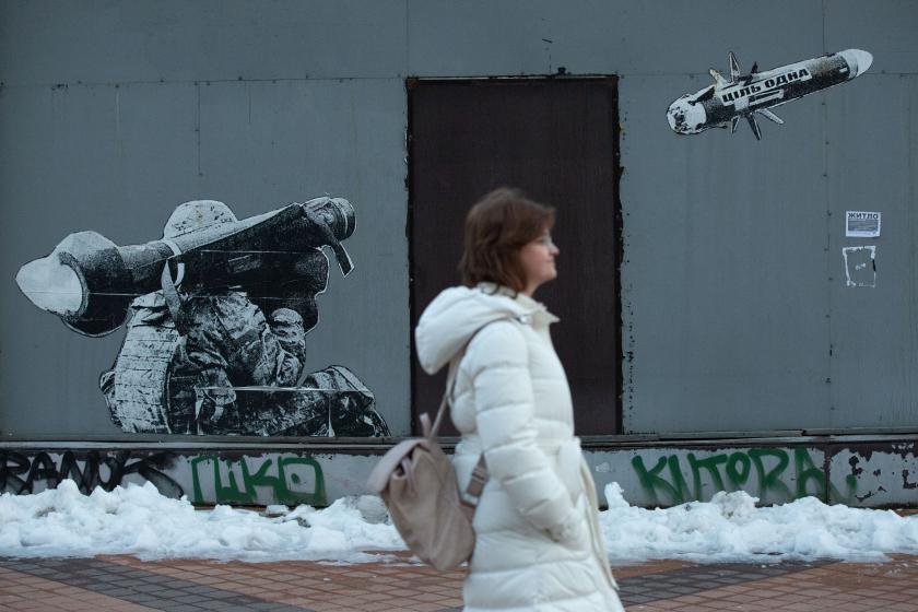 Rusya'ya karşı savaşın devam ettiği Ukrayna'nın başkenti Kiev'de, Ukraynalı bir askerin ABD yapımı Javelin taşınabilir tanksavar füze sistemiyle ateş ettiğini gösteren bir grafitinin önünde yürüyen bir kadın.