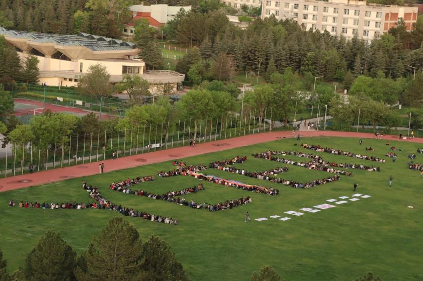 Stadyumda yan yana durarak 'YETER' yazısı yazan öğrenciler