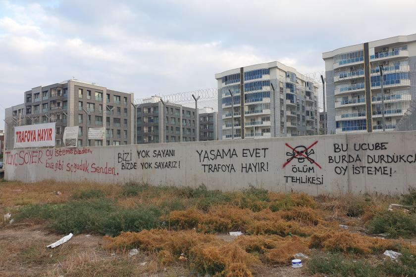 Mahallede apartmanların önünde yükselen, tellerle örtülmüş, üzerinde 'yaşama evet, trafoya hayır' yazılı duvar