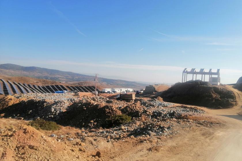 Foça yakınlarındaki ekoköy projesinin beyaz, üzerinde ekoköy projesine ilişkin fotoğraflar bulunan tabelası.