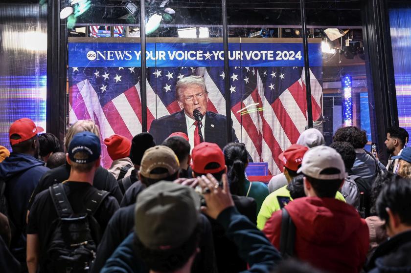 Donald Trump'ın konuşmasının yer aldığı vitrini izleyen  sokaktakiler