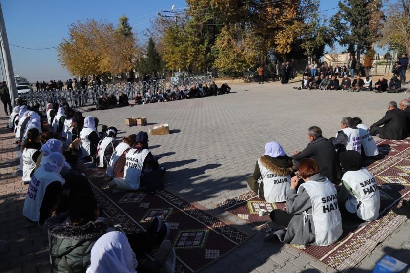 polis bariyerlerinin karşısında oturan bir grup insan