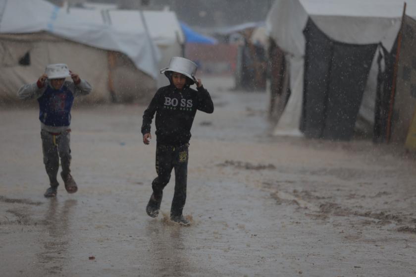 Gazze'de yağmurda yürüyen çocuklar