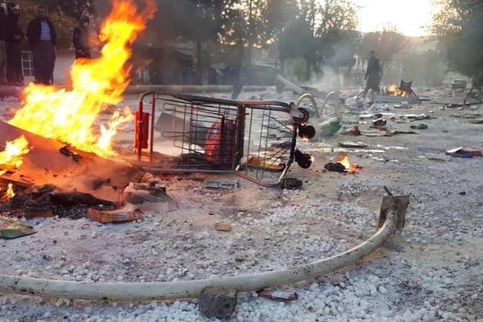 İran'daki protesto gösterileri sırasında sokaktan çekilmiş bir fotoğraf (Yolun ortasında devrilmiş bir alışveriş arabası ve yanan bir ateş)