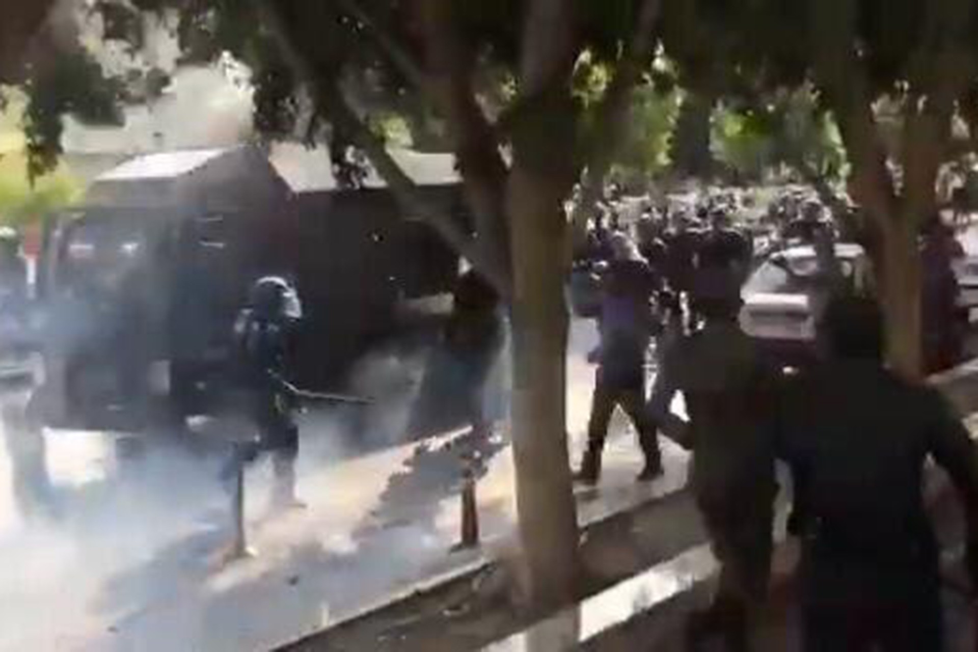 İran'daki protesto gösterileri sırasında polisin biber gazı ve cop kullandığı andan bir fotoğraf