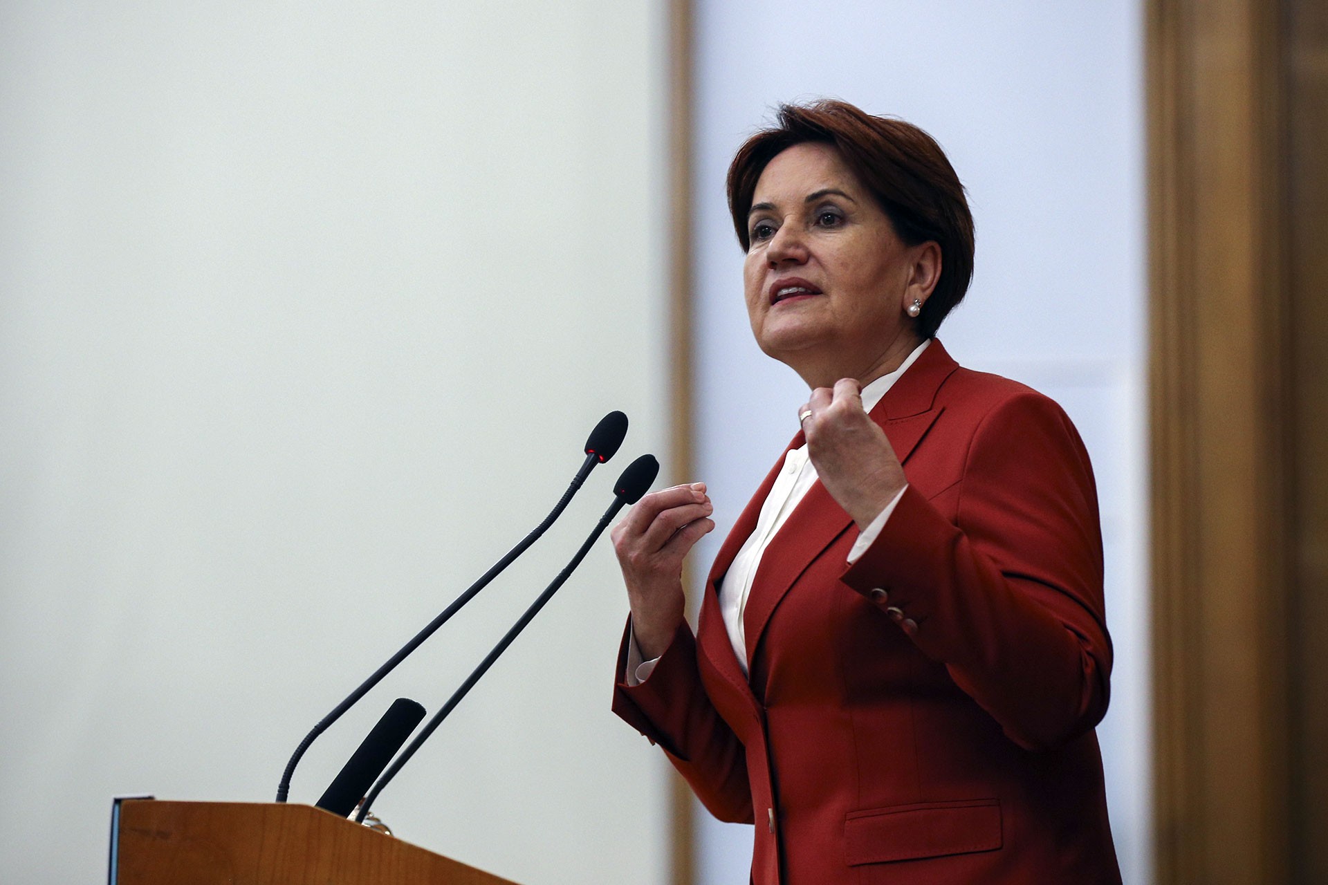 Meral Akşener, kürsüde kırmızı ceketiyle konuşma yapıyor.