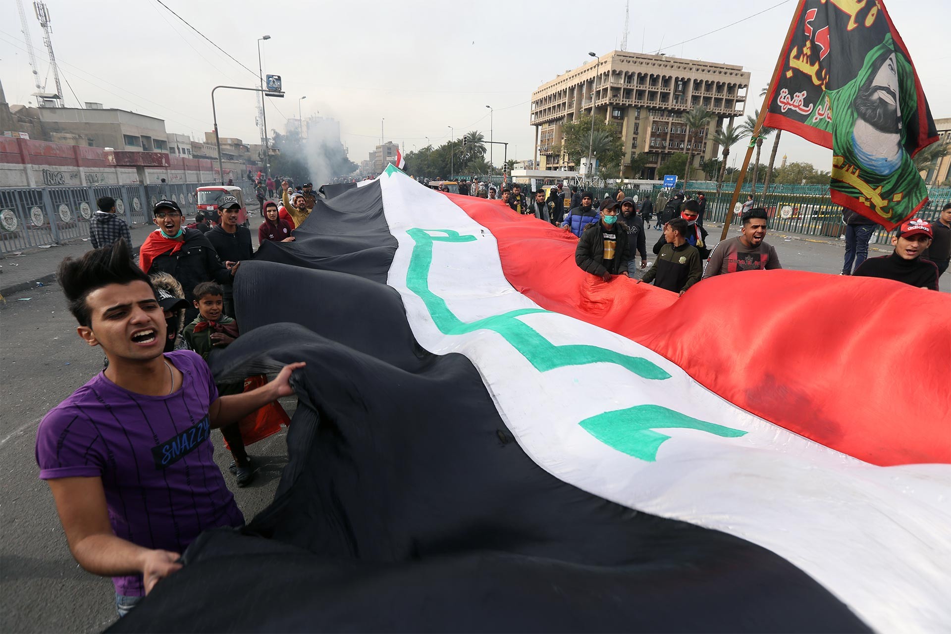 Irak'ta hükümeti protesto için sokağa çıkan halk elinde Irak bayrağı taşıyor