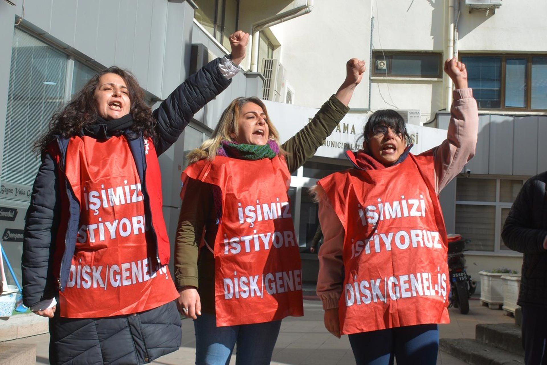 Bergama Belediyesinden atılan kadın işçiler, üzerlerinde 'İşimizi istiyoruz' yazılı önlüklerle belediye binası önünde eylemlerini sürdürürken.