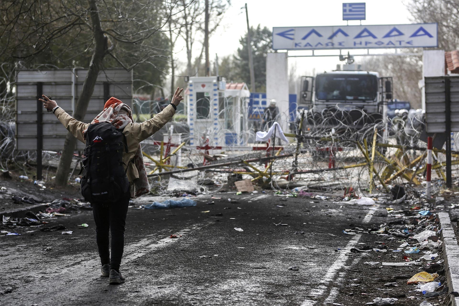 Yunanistan tarafından atılan gaz bombalarına karşı zafer işareti yapan mülteci