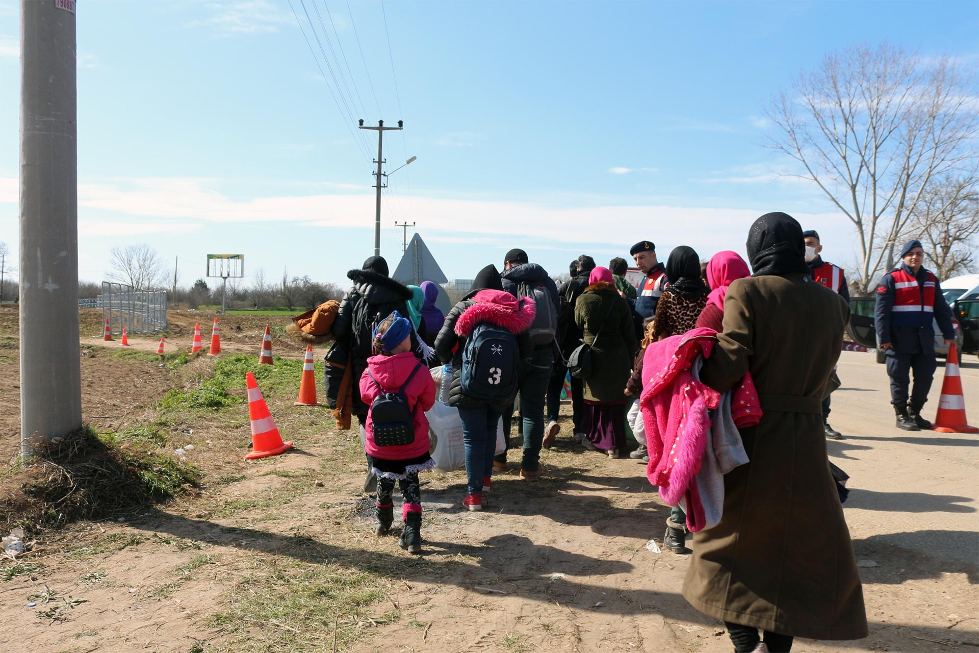 Sınıra doğru yürüyen mülteciler ve jandarma ekibi