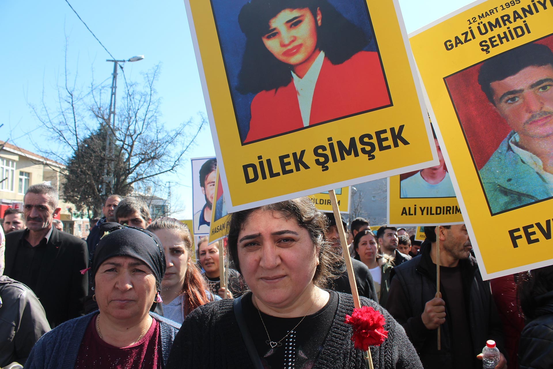 Elinde Gazi Katliamı'nda yaşamını yitiren Dilek Şimşek'in fotoğrafının olduğu dövizi taşıyan bir kadın. 