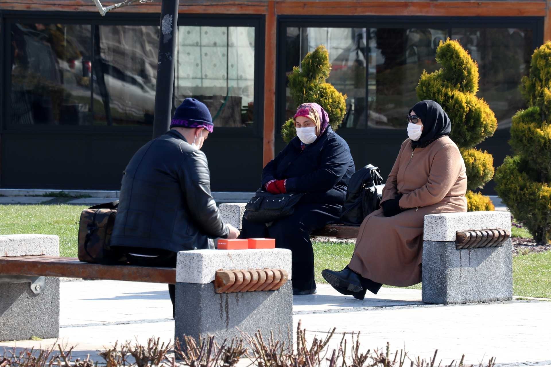 Sivas'ta kent meydanında banklarda oturan ve koronavirüs (Kovid-19) salgını dolayısıyla ağız ve burunlarını maskeyle kapatan insanlar.