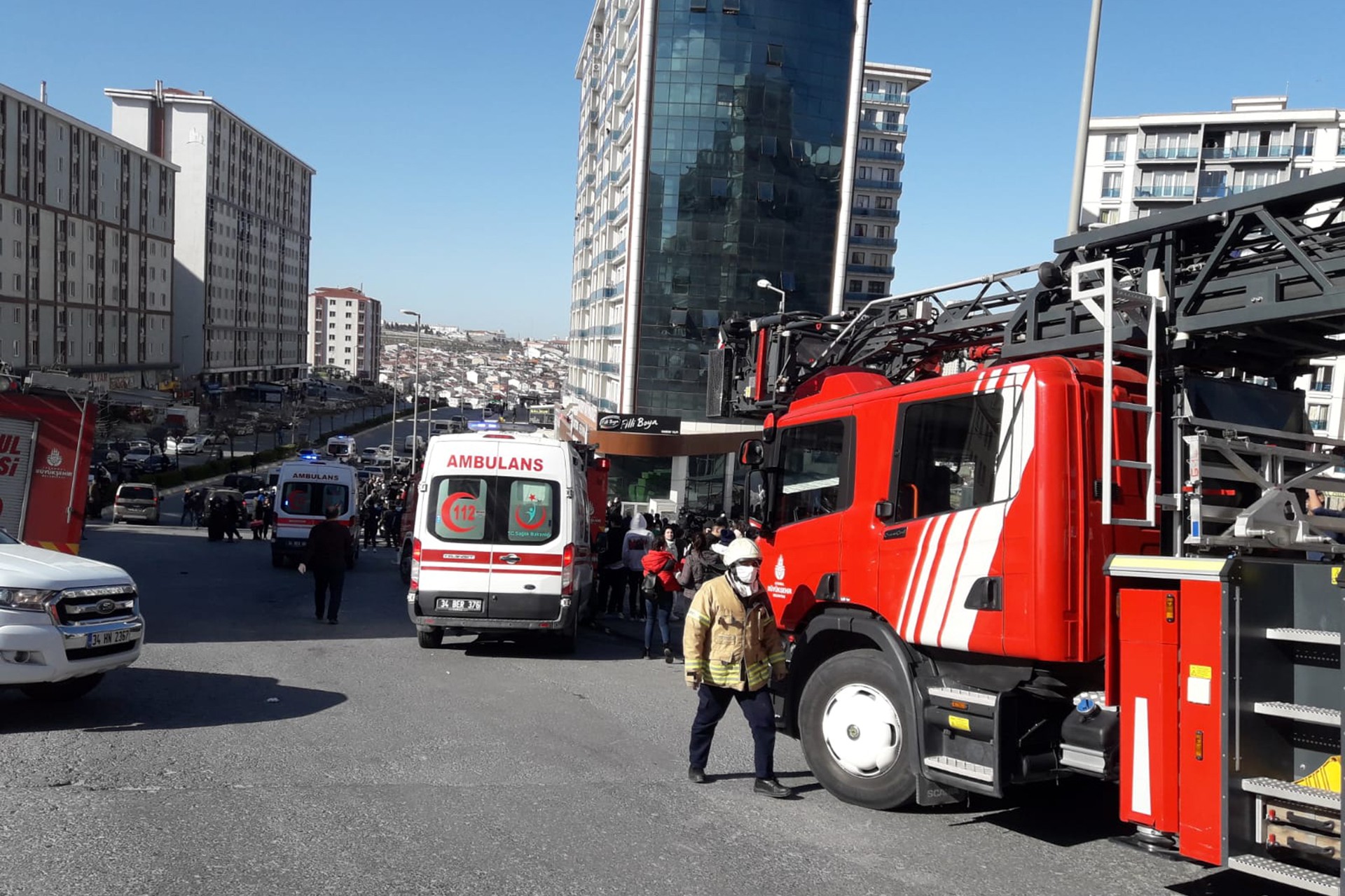 İtfaiye aracı (sağda), ambulans (ortada) ve ileride patlamanın olduğu bina ve insan kalabalığı