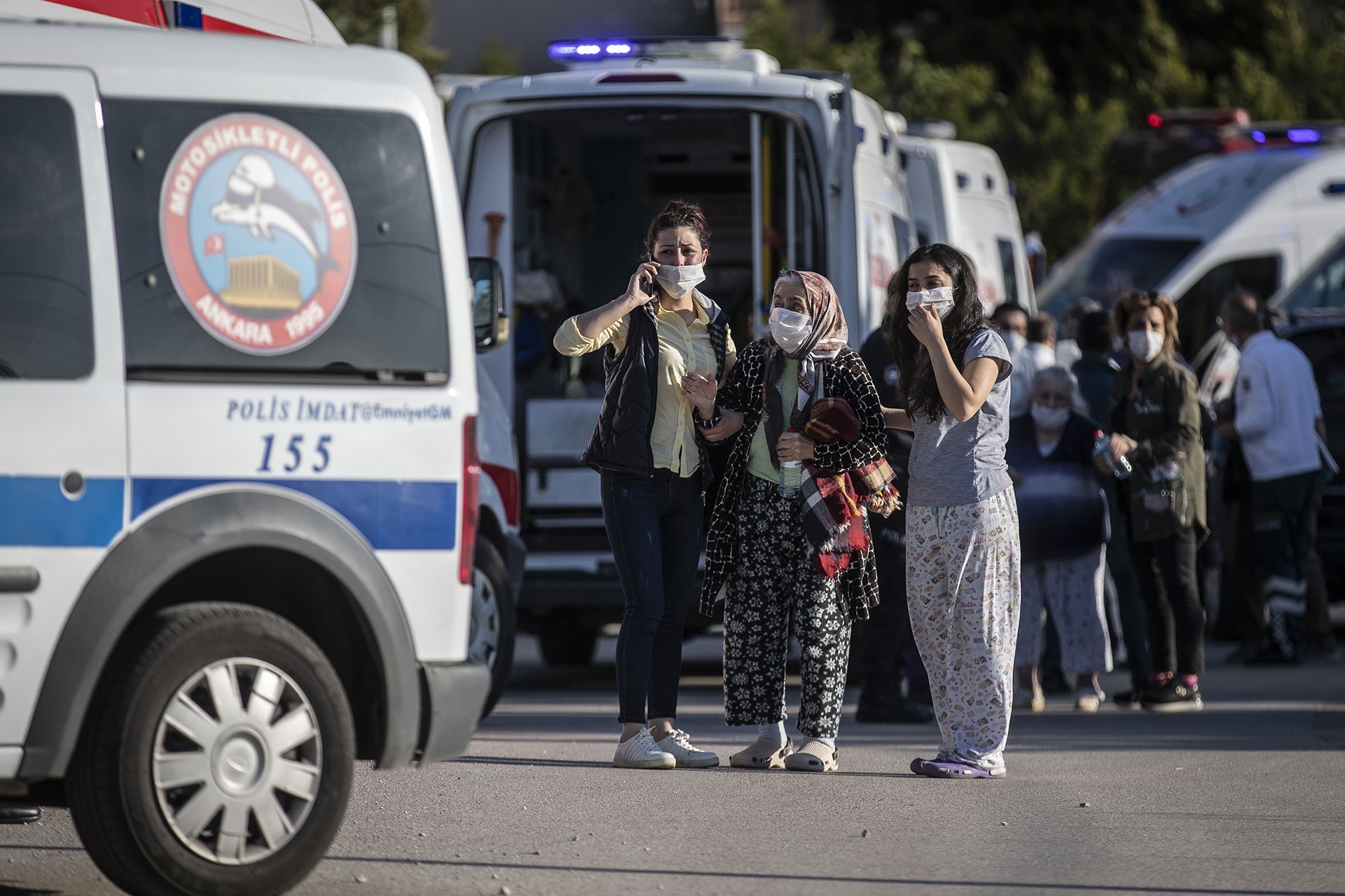 Yaşlı bir kadını ambulansa götüren yakınları.