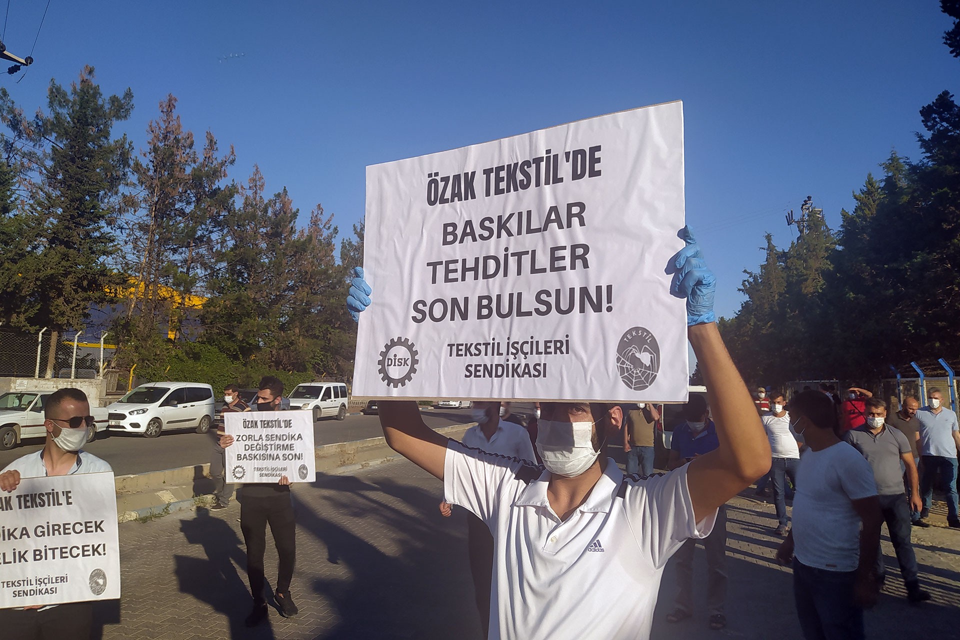 Özak tekstilde baskılar tehditler son bulsun yazılı döviz tutan bir işçi