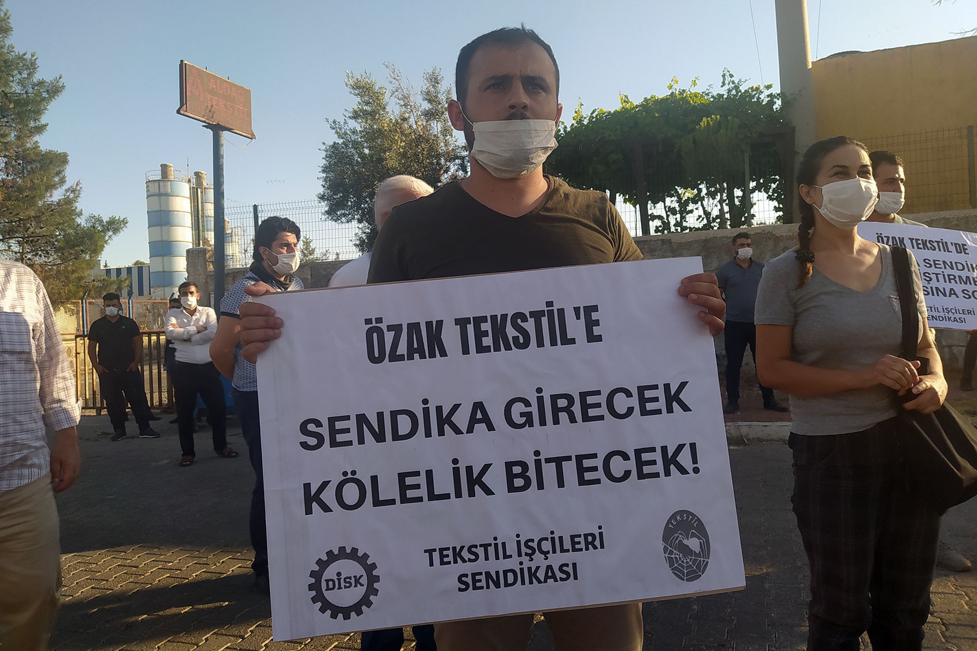 ÖZAK tekstile sendika girecek kölelik bitecek yazılı döviz tutan bir işçi