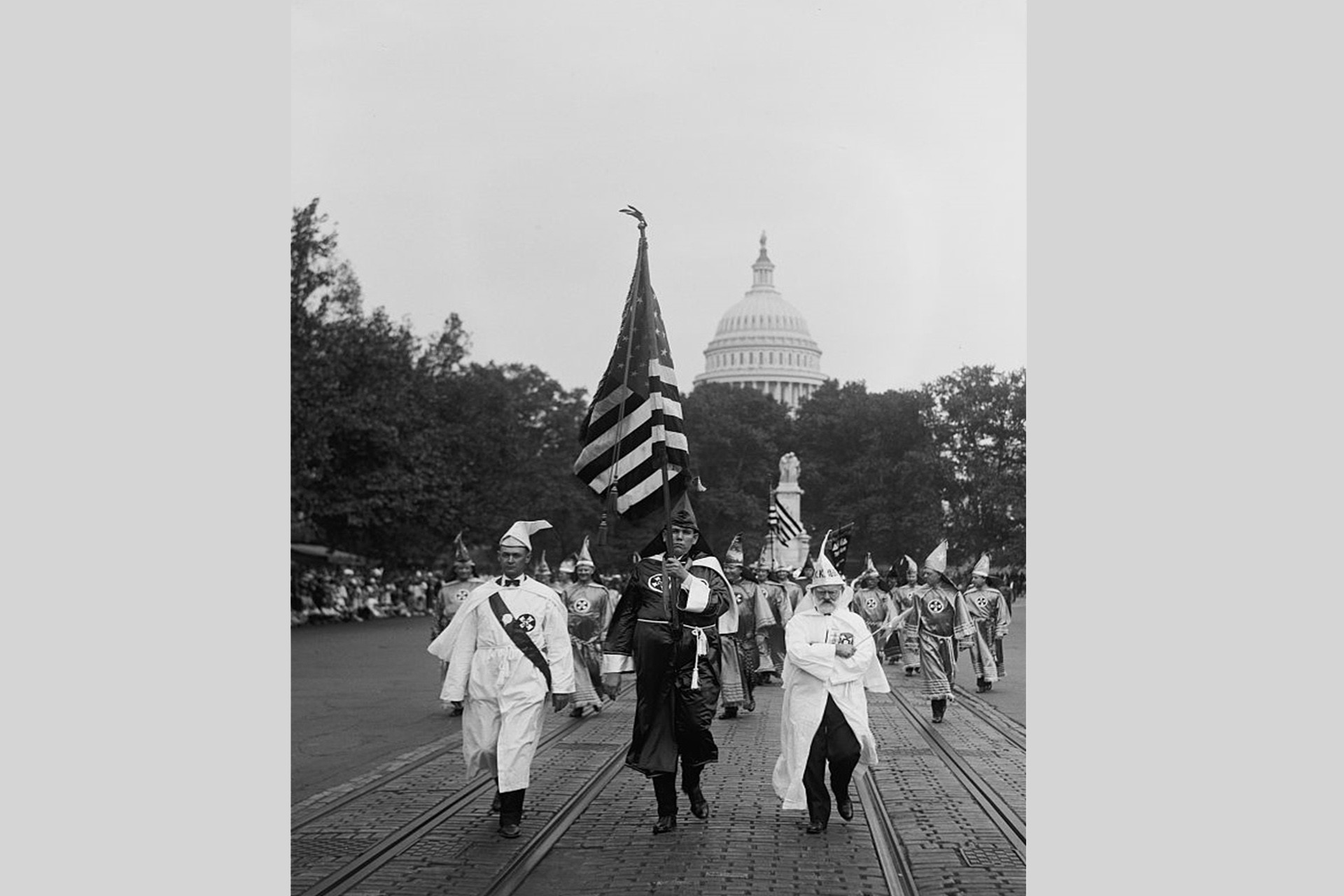 Ellerinde Amerikan bayrağıyla Ku Klux Klan üyeleri Beyaz Sarayın önünde geçiş yapıyor, yıl 1926 