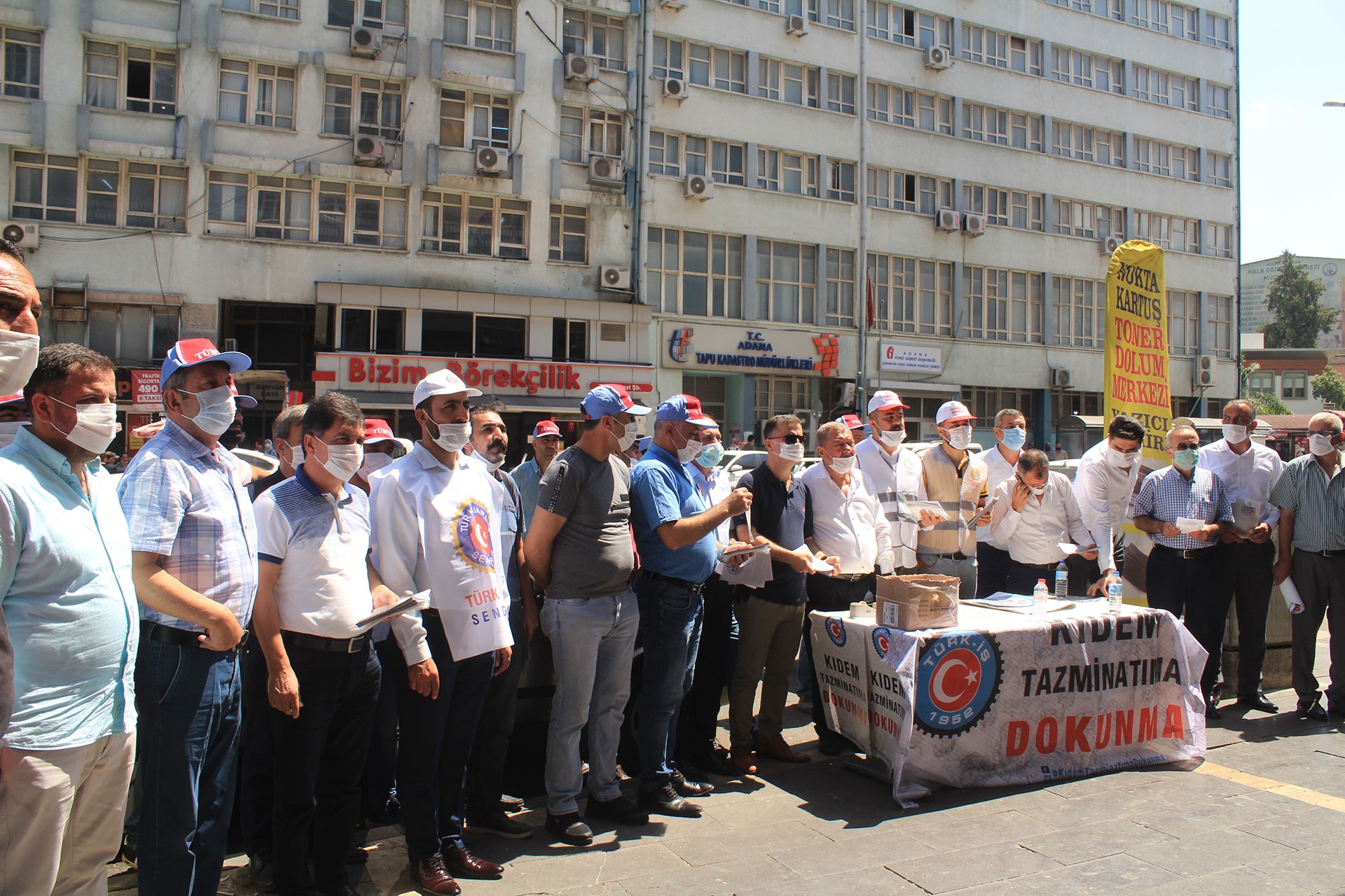 Kıdem Tazminatıma Dokunma yazılı masanın etrafında Türk-İş üyeleri